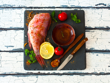 Fillet of red grouper and spices, tomatoes, parsley , lemon and olive oil over natural background
