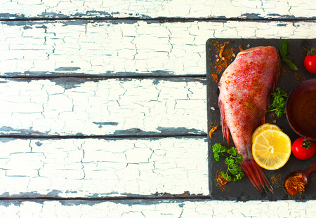 Fillet of red grouper and spices, tomatoes, parsley , lemon and olive oil over natural background