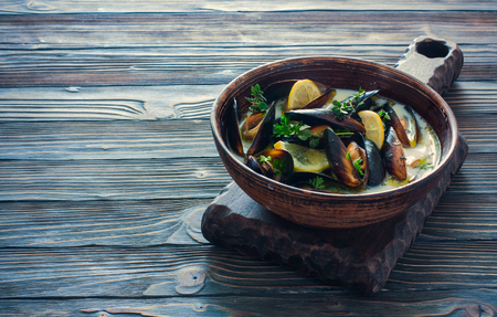 Mussels with brouth, lemon and herbs  in clay pot over dark  wood backgroundの写真素材