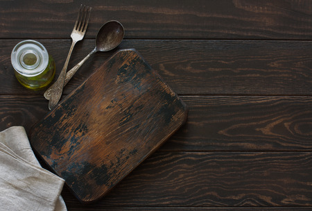 Empty old cutting board, vintage spoon and fork  over old wood background. Top view. Copy spaceの写真素材