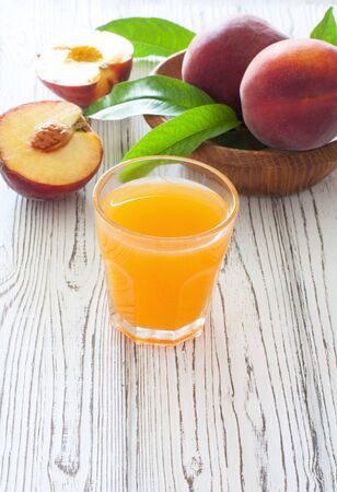 Ripe peaches and glass of peach juice over white wood background. Copy spaceの写真素材