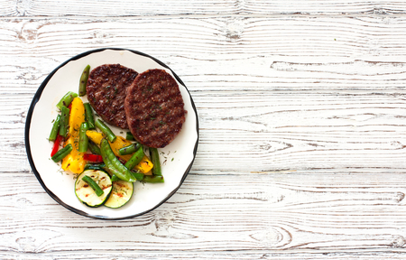 Beefsteaks grilled with vegetables in white plate on a white wood background. Top view. Copy spaceの写真素材