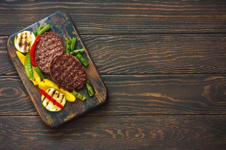 Beefsteak grilled with vegetables on a dark wood background. Top view. Copy spaceの写真素材