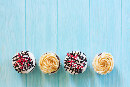 Vanilla and chocolate cupkcake with meringue on blue wood background. Top view. Copy spaceの写真素材