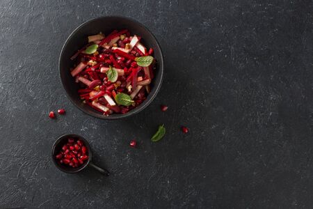 Beetroot, apple and red beans vegan salad in a black plate on a black stone background close up. Flat lay. Copy spaceの写真素材