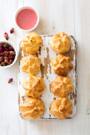 Homemade profiteroles on wooden cutting board close up. Flat layの写真素材