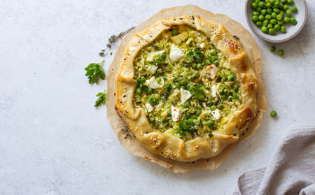 Cabbage, green peas and feta cheese open face pie (galette) close up on gray stone backgound. Flat lay. Copy spaceの写真素材