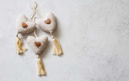 Decorative handmade textile hearts on light stone background. Flat lay. Copy spaceの写真素材