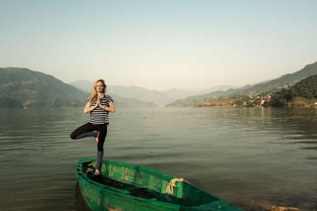 Girl doing morning sports fitness exercises near  mountain lake outdoor. Yoga tour, relaxationの写真素材