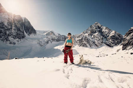 Young Happy Woman doing photo, enjoy and sunbathing in winter mountains with dogの写真素材
