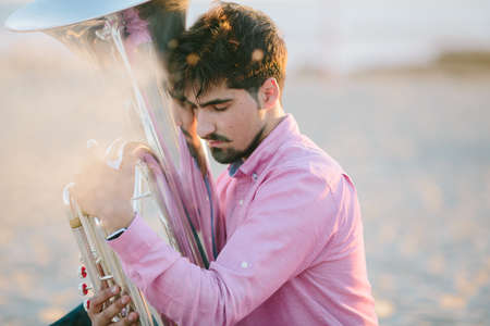 Young man with Tuba musical instrument  on sea shore  outdoorの写真素材