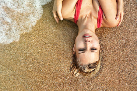 Beautiful wet woman face with water drop. Close-up portrait on the beach backgroundの写真素材