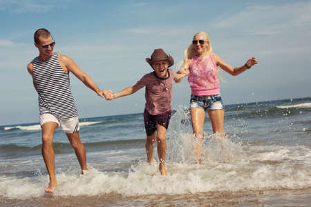 Happy young family having fun running on beach. Family traveling conceptの写真素材