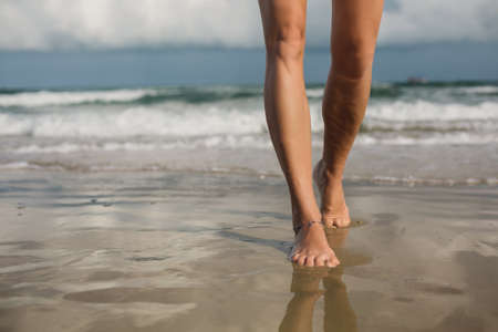 Woman walking on sand beach. Closeup detail of female feet, beach travelの写真素材