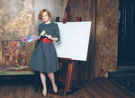 Beautiful woman artist with a blank canvas and brushes in luxury interiorの写真素材
