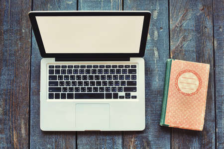 Open Laptop Computer and old book on wooden backgroundの写真素材