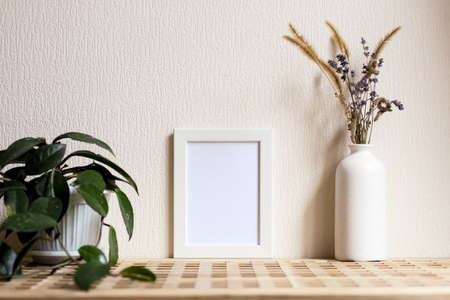 Poster with copy space. Mockup of a wooden frame with home plant liana with vase with dried flowers....