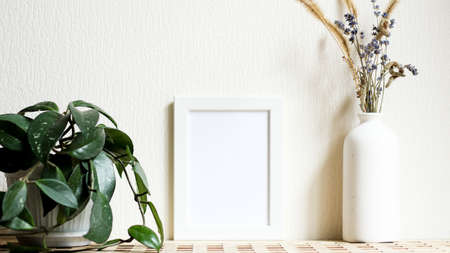 Poster with copy space. Mockup of a wooden frame with home plant liana with vase with dried flowers....