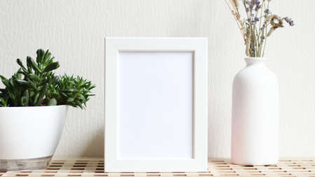 Poster with copy space. Mockup of a wooden frame with home plant succulents, with vase with dried...