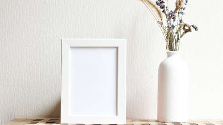 Poster with copy space. Mockup of a wooden frame with with vase with dried flowers. White, minimalism. copy space. Mock up design.の写真素材
