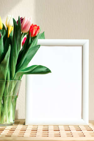 Poster with copy space in warm shades . Mockup of a wooden frame with tulips. White, minimalism. copy space. Mock up design.の写真素材