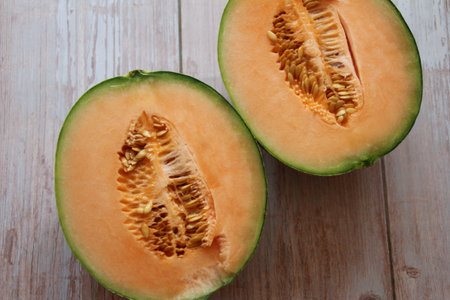 an orange melon cut in half, with the seeds in the center
