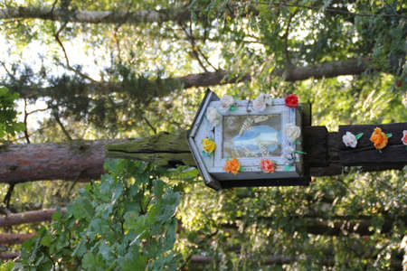 a small chapel in a tree with the Virgin Mary, decorated with colorful flowersの写真素材