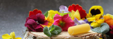 tortellini pasta, Italian pasta, a cut piece of wood and scattered spring flowers, tube pastaの写真素材