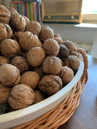 walnuts in a basket, nuts without slate, a pile of nuts, in the background an old radio and booksの写真素材