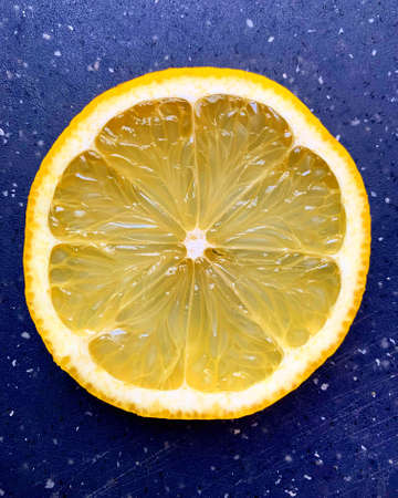 juicy lemon slice, yellow lemon, fruit slice on a navy blue board, citrus, sour fruitの写真素材