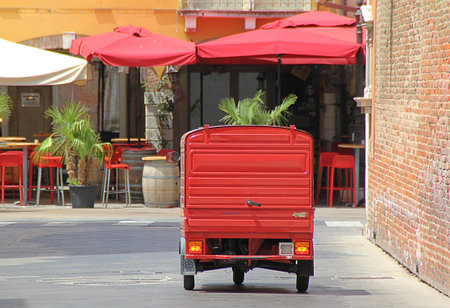 a small car on three wheels, an ape car, a red toy car for carrying goods, an Italian town with...