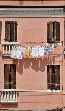 orange house with laundry hanging, laundry lines nailed to the wall, brown wooden shutters, white T-shirts on a lineの写真素材