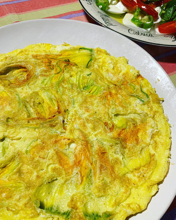 omelette with zucchini flowers, fresh egg omelette, salad with tomatoes and mozzarella, breakfast dish plateの写真素材