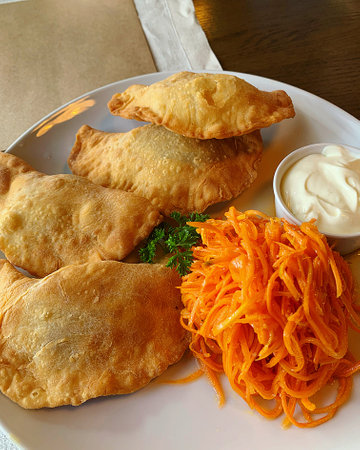 Fried dumplings with carrots and sour cream on a plate, fried dumplings, stuffed dumplings, carrot salad, mayonnaise sauce, Ukrainian dumplings, lunch dishの写真素材