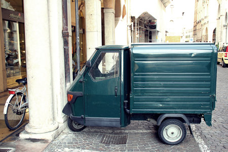 truck on the street in the old city, small green tricycle car, italian ape car, ape car, small toy car with one wheel in front, street in a town in italyの写真素材