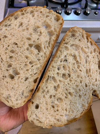 Sliced bread on a wooden cutting board on the kitchen stove, resh crusty bread, artisan wheat bread,...