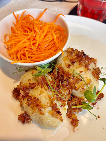 fried dumplings with carrot on a white plate in a restaurant, zeppelins, meatballs made of flour and...