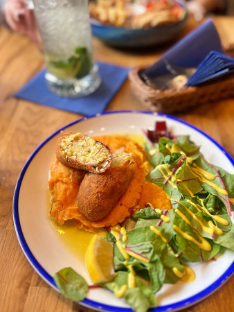 cod meatballs, sweet potato puree, young beetroot leaves, a dish in a restaurantの写真素材