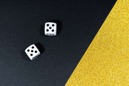 Two white dice on a shiny gold and black paperの写真素材