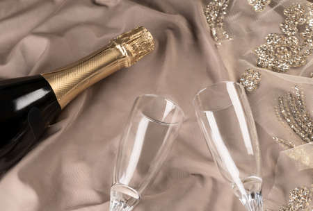 Two glasses and a bottle of champagne on a festive textured nude background with gold decor. View from above. Festive concept.の写真素材