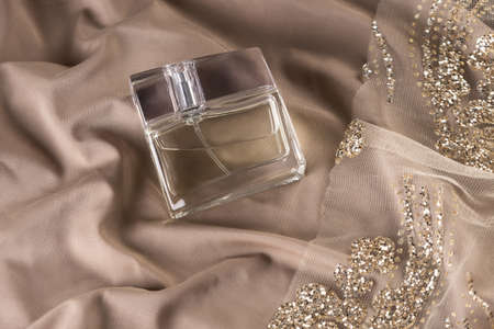 A beautiful bottle of perfume on a textured fabric  with gold decorの写真素材