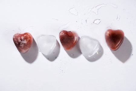 Heart shaped ice with strawberries against white background.の写真素材