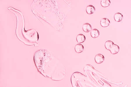 Drops of different forms of hyaluronic acid, pink background. Cosmetics concept.の写真素材