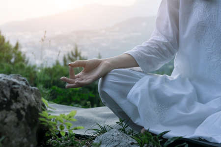Beautiful young woman practices yoga and meditates on the mountain. Calmness and unity with nature.