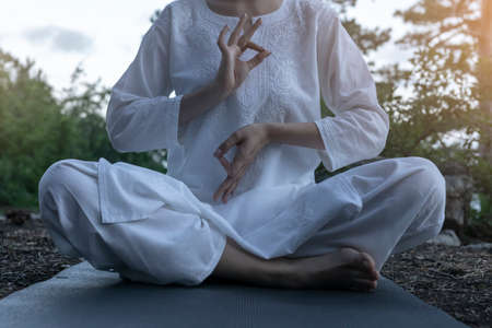 Beautiful young woman practices yoga and meditates on the mountain. Calmness and unity with nature.の写真素材
