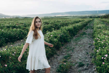 Beautiful young natural girl outdoors in the rays of the setting sun. Delicate young blonde in a summer dress enjoying the nature and freedom of the summer sunset.の写真素材