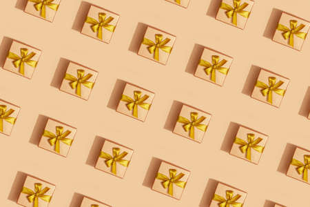 Pattern of golden holiday boxes with ribbon on a yellow background. Festive pattern background.