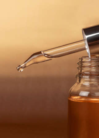 Cosmetic pipette close-up and bottle of cosmetic product, oil or hyaluronic acid on a gold background.の写真素材