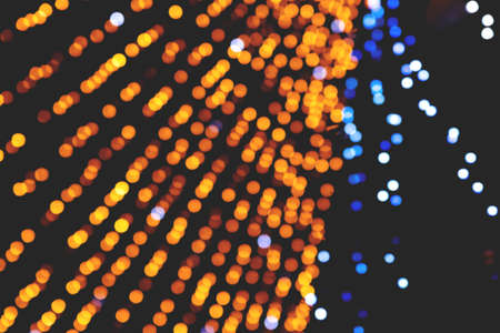 Blurred holographic background with bright rainbow sparkles. Blurred golden festive lights.