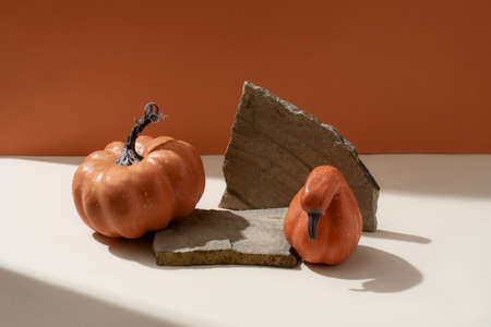 Creative Fall layout made of pumpkins. Halloween holiday concept. Pumpkins on a stone stand, orange background.の写真素材